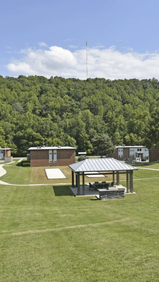 a grassy field with a picnic area and a building at The  Park At Fountain City